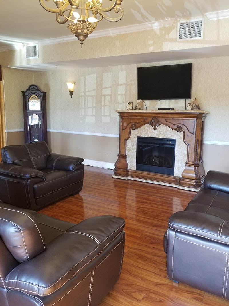 A cozy living room featuring a fireplace with an ornate mantelpiece, leather sofas, and a television mounted above the hearth.