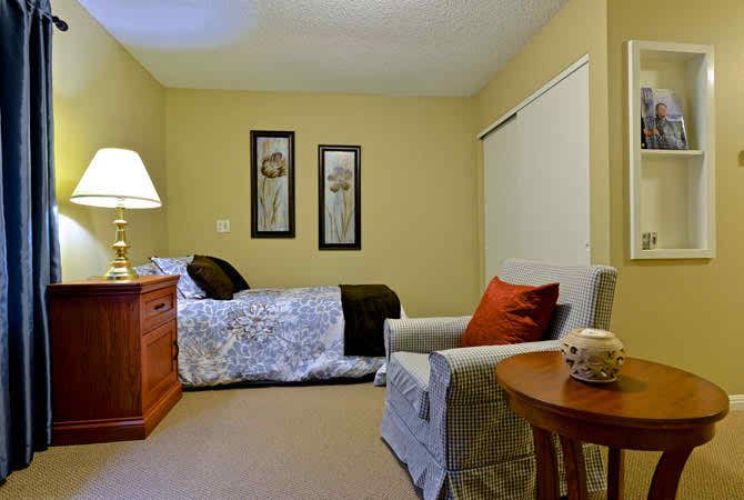 A cozy bedroom with a bed, armchair, and warm lighting.