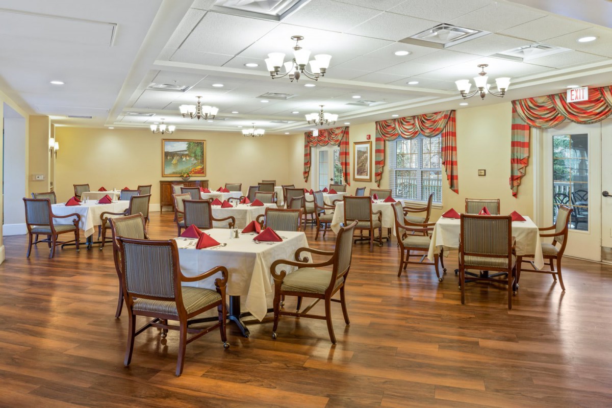An elegant dining room interior with neatly arranged tables and chairs on a wooden floor.