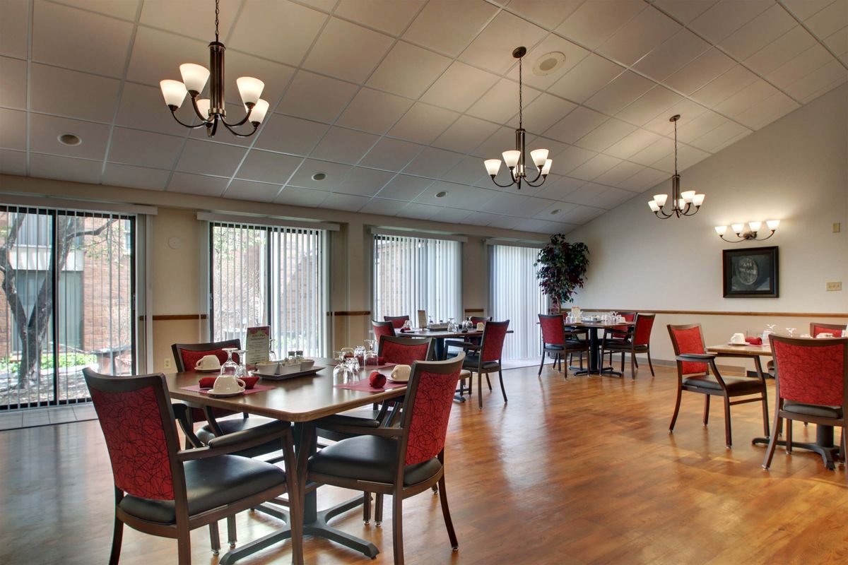 A cozy dining area with elegant chandeliers and red cushioned chairs.