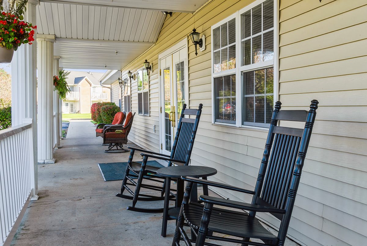 A cozy covered porch with black rocking chairs and a small table.