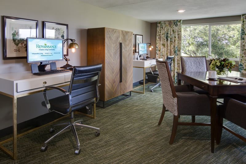 A modern office workspace with desks, computers, and ergonomic chairs.