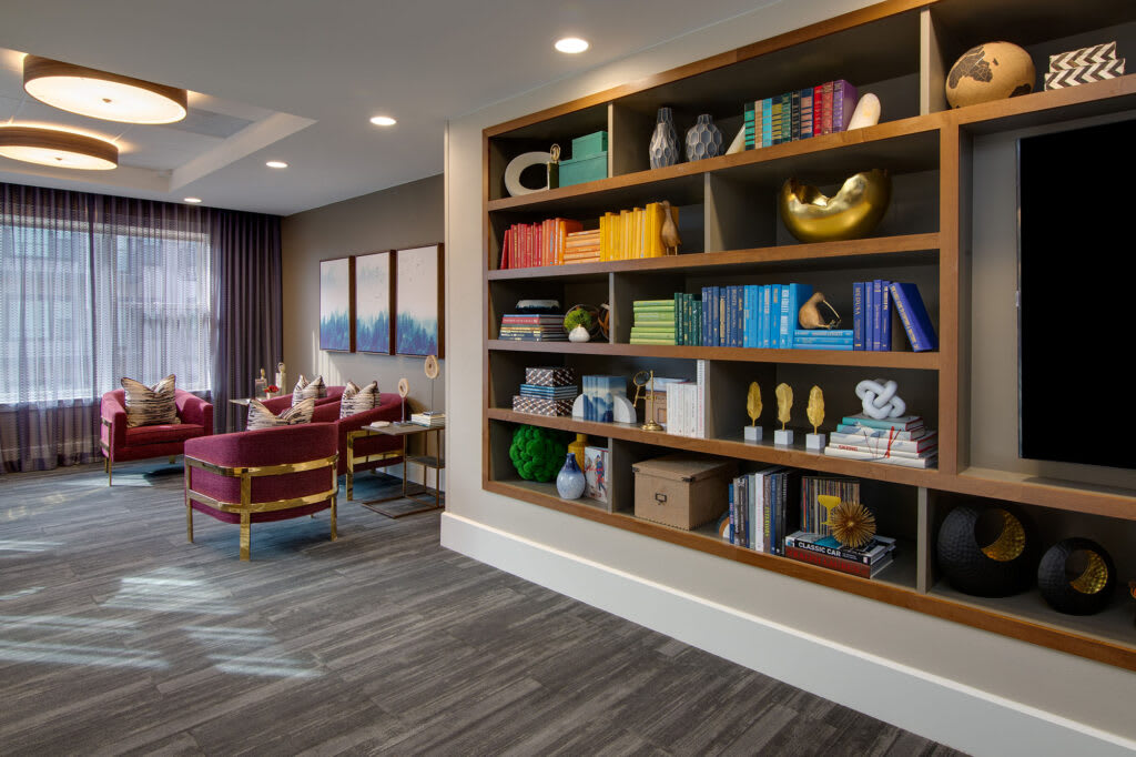 A modern lounge area featuring a colorful bookshelf and comfortable seating.