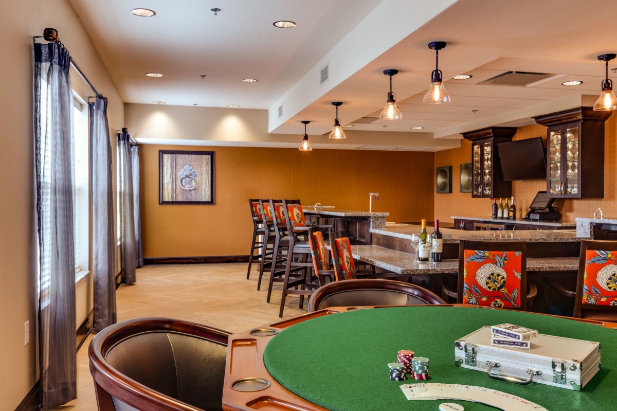 A cozy room featuring a poker table and a bar area with ample seating.