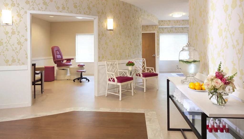A bright and welcoming waiting area with floral wallpaper and modern seating.