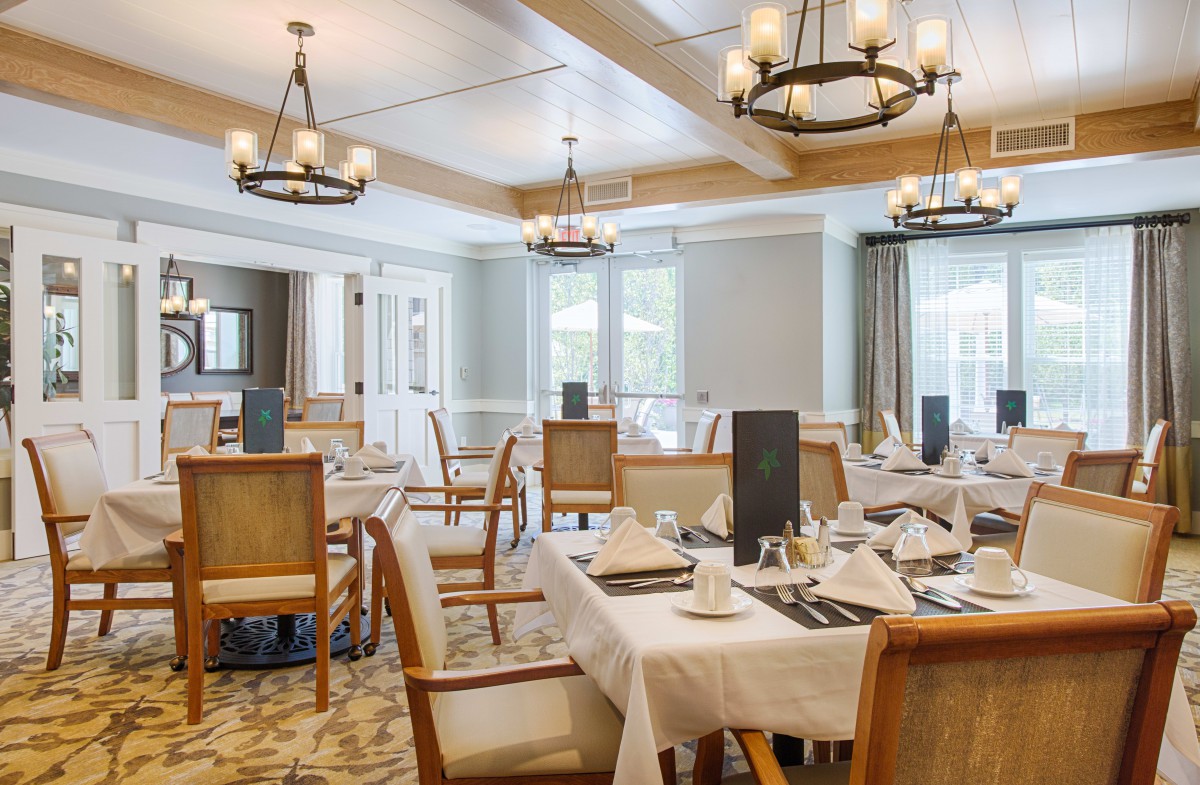 An elegant restaurant dining room with neatly arranged tables and classic chandeliers.