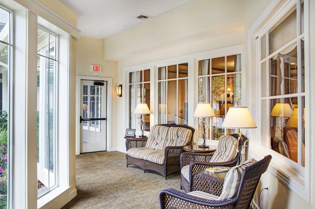 A cozy seating area with wicker furniture and large windows allowing natural light.