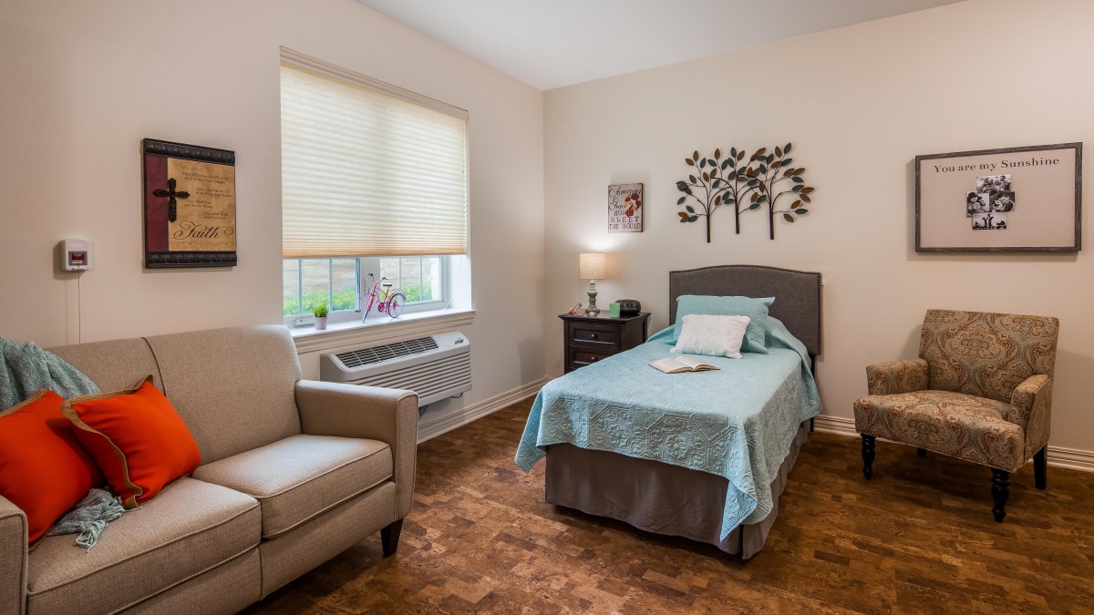 A cozy, minimalist bedroom with a single bed, wall decor, and comfortable seating.