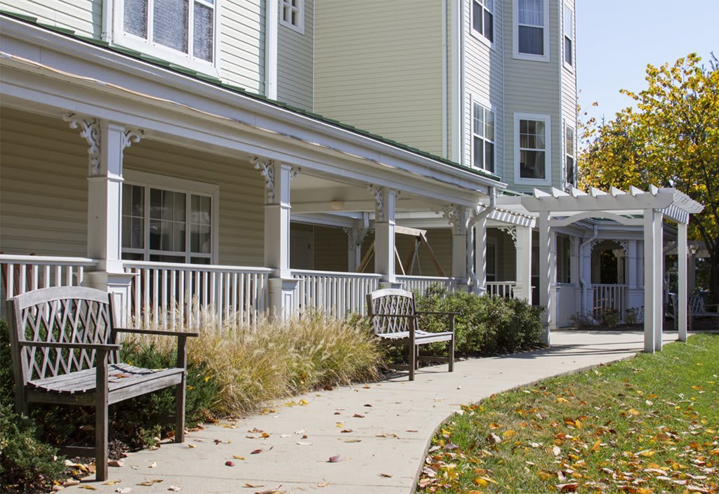 A residential building with a porch and outdoor seating along a curved pathway.