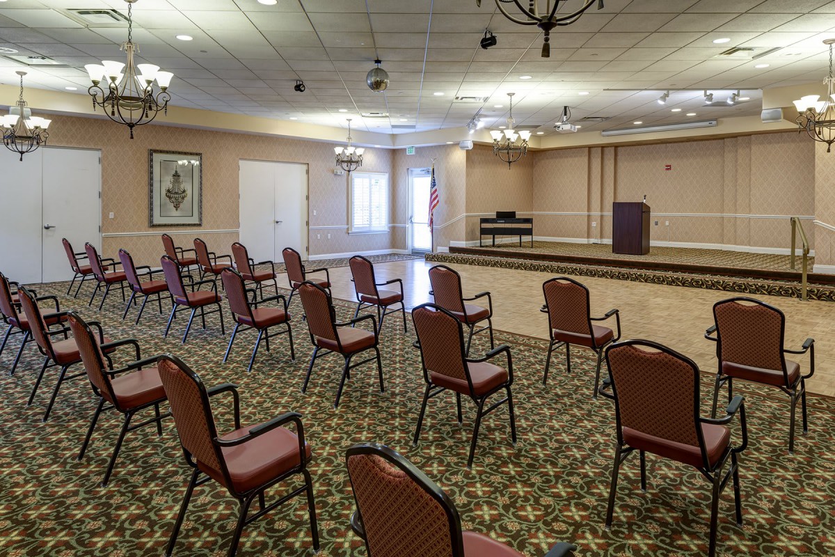 An empty conference room with rows of chairs facing a stage.