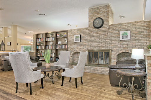 A cozy modern living room featuring a brick fireplace, stylish armchairs, and a well-stocked bookshelf.
