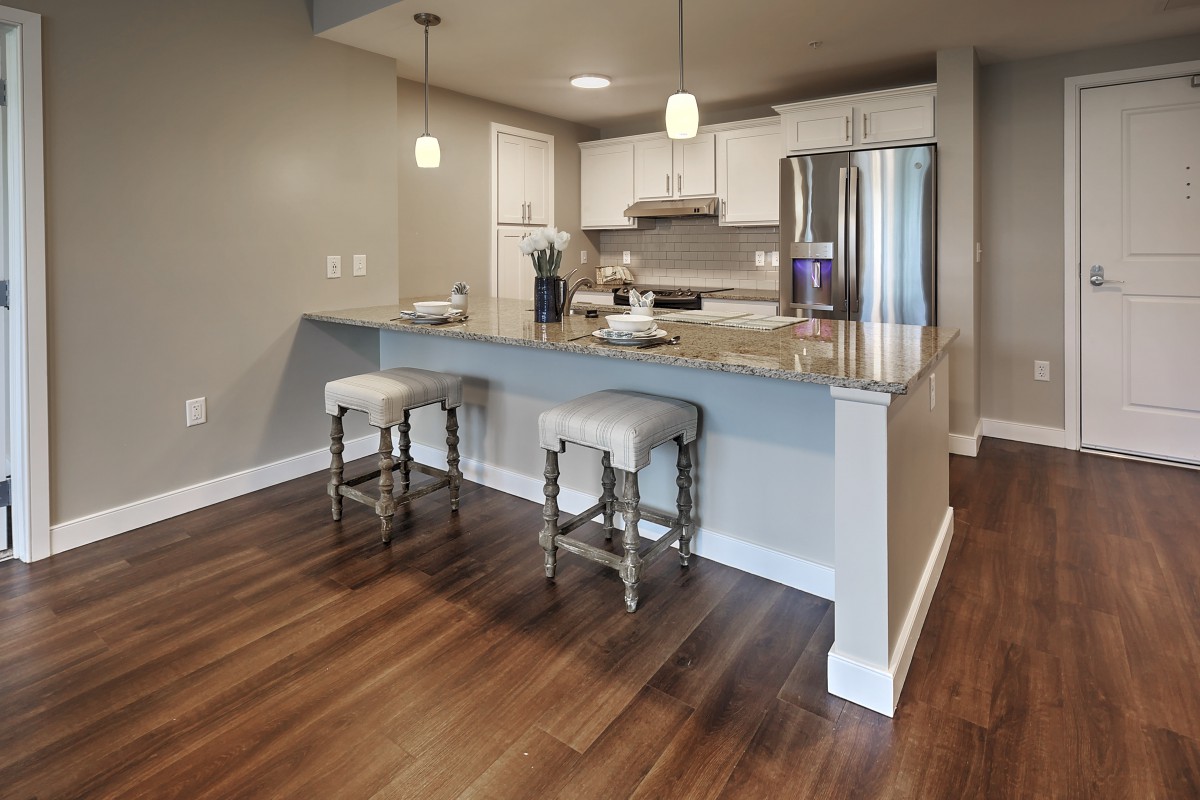 Modern kitchen with granite countertops and bar stools.