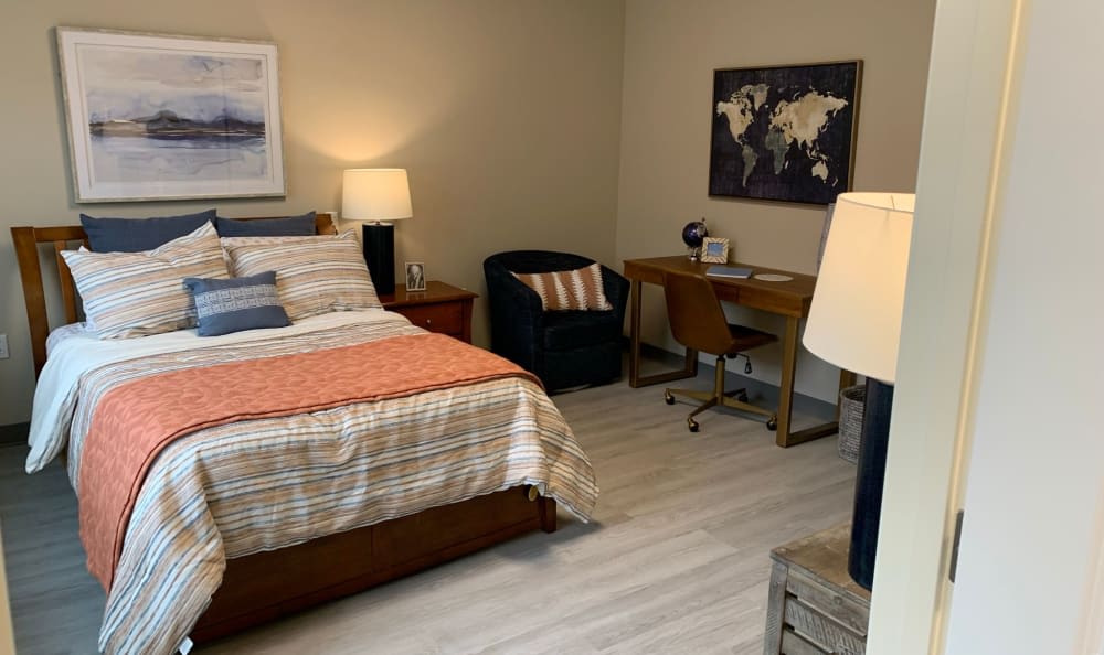 A cozy bedroom with a bed, desk, and map artwork.