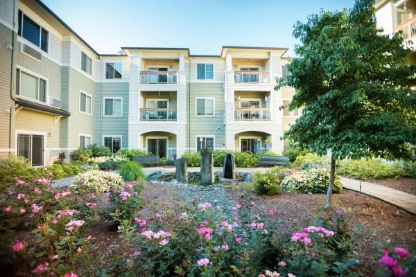 A residential apartment building with beautifully landscaped gardens and vibrant flowers.