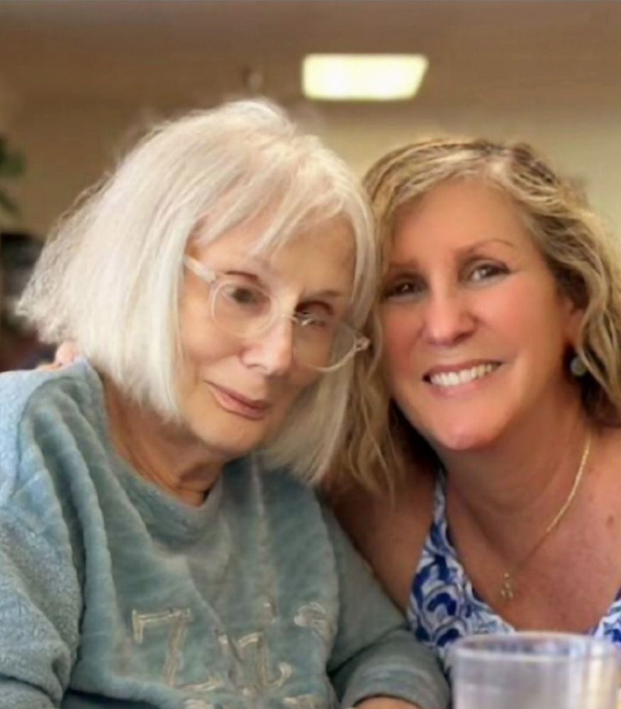 Two women smiling together indoors.