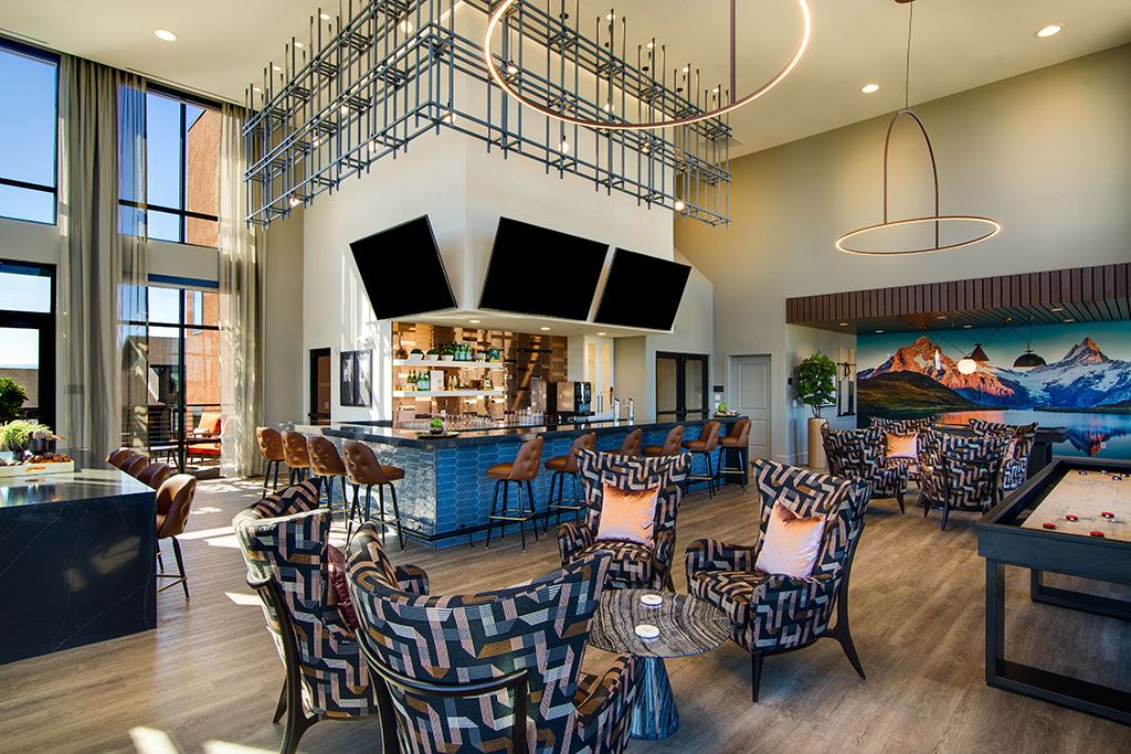 A modern lounge area featuring a stylish bar, multiple seating arrangements, and decorative lighting.