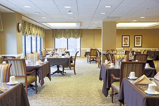 A spacious and well-lit dining room with neatly arranged tables and chairs.