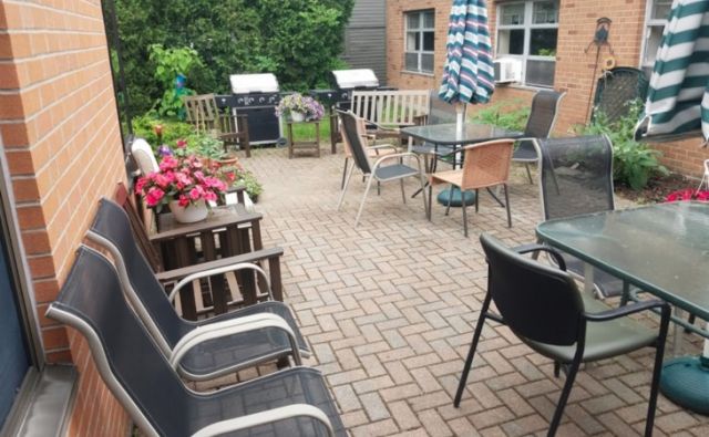 A cozy outdoor patio with seating, tables, an umbrella, and a garden view.