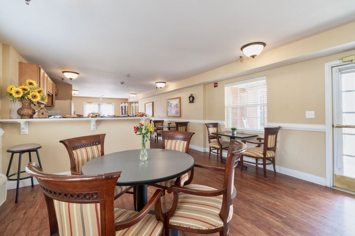 A cozy dining space with wooden chairs and tables, complemented by soft lighting and wood flooring.