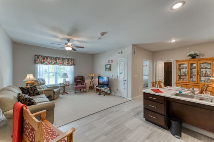 A modern open floor plan living room connected to a kitchen, featuring comfortable furniture and natural lighting.