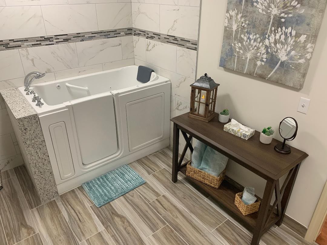 A well-decorated bathroom featuring a walk-in bathtub, wooden floors, and stylish decor.