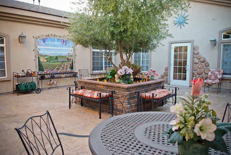 A beautifully decorated courtyard featuring outdoor seating, a central tree, and a welcoming atmosphere.