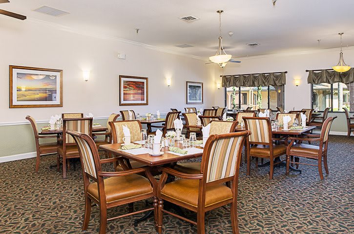 A neatly arranged dining area with several tables and chairs, set for guests.