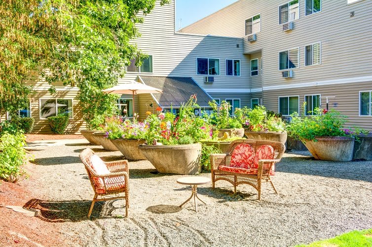 A sunny courtyard garden with chairs and tables in an apartment complex.