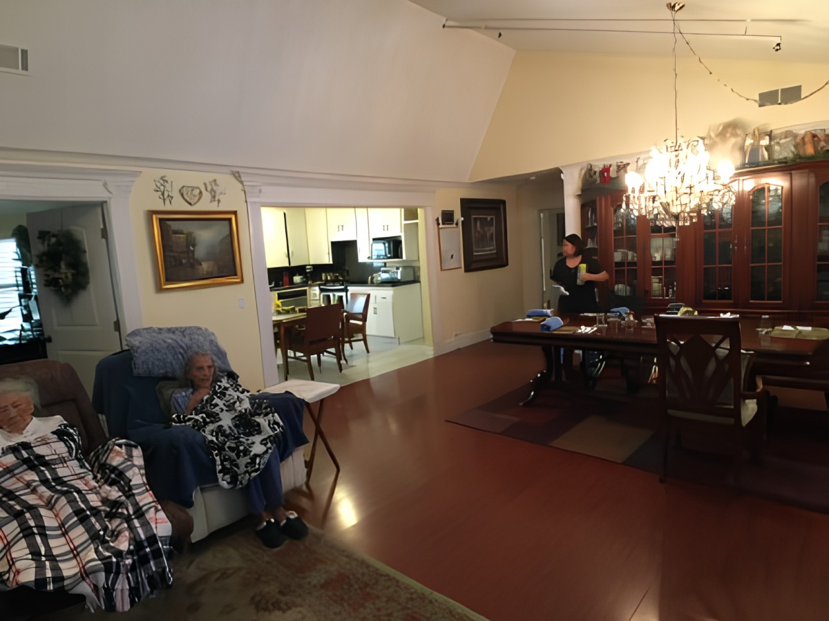 A cozy living and dining area with a chandelier, featuring a glimpse into the kitchen.