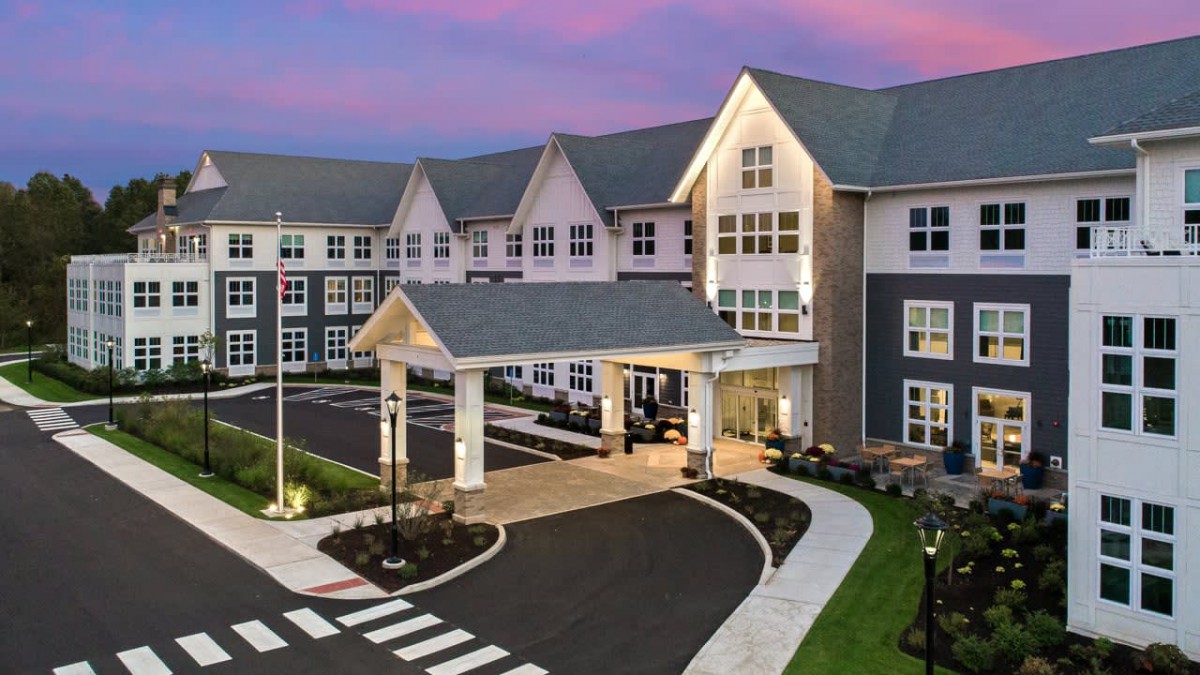 A modern residential building with a welcoming entrance and driveway at sunset.