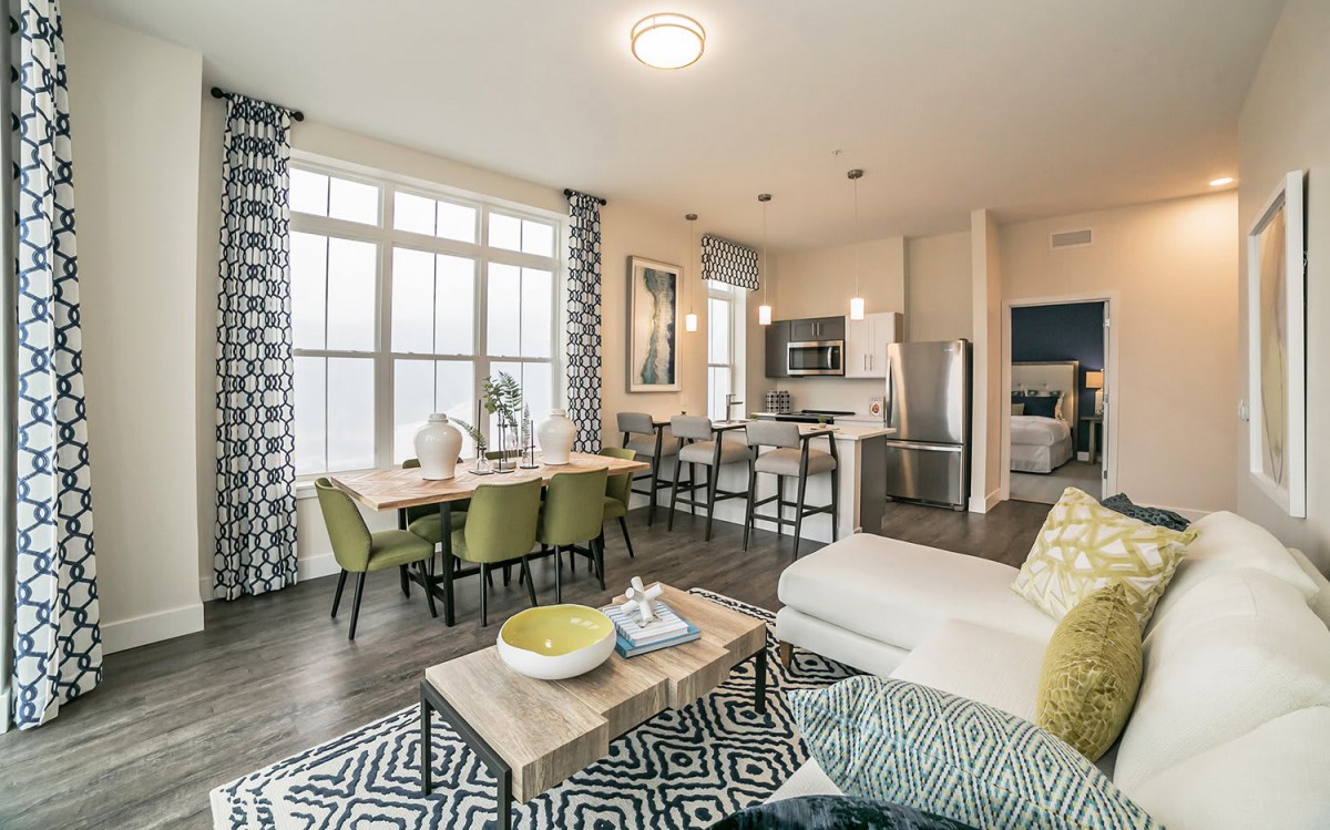 A modern open floor plan living room with a dining area and kitchen, featuring stylish decor and furniture.