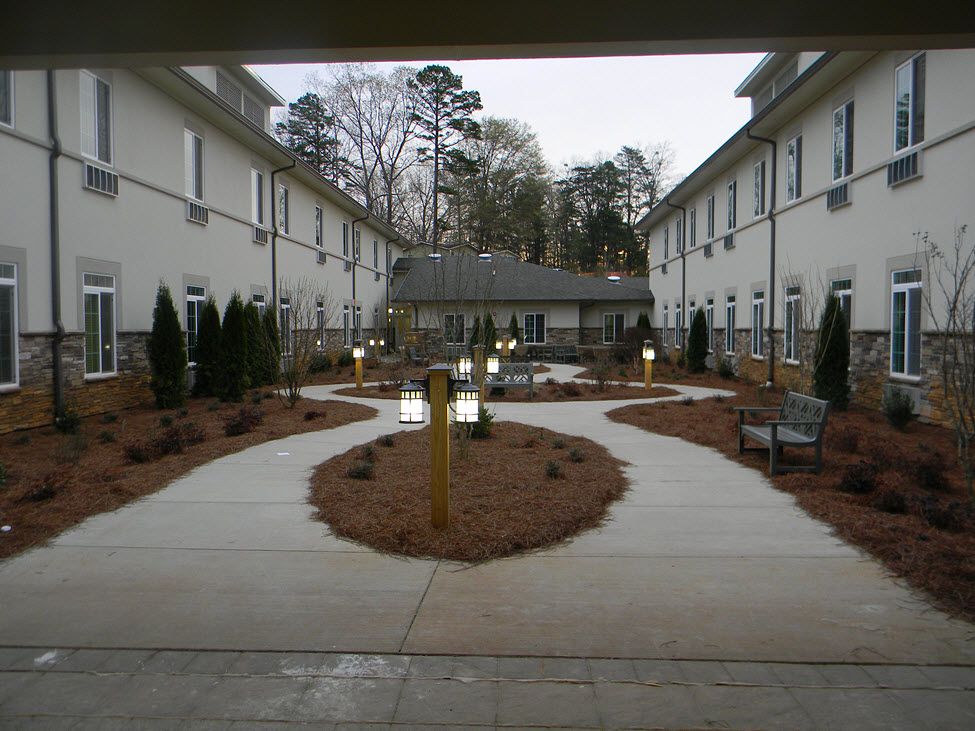 A well-maintained courtyard with paved pathways and greenery between two buildings.