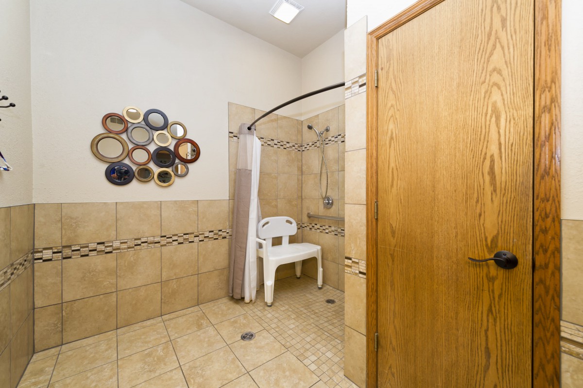 An accessible bathroom featuring a shower with a chair and decorative wall accents.