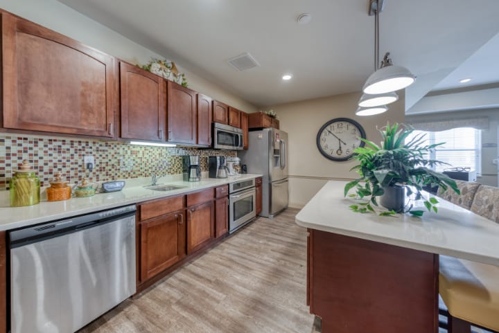 A modern kitchen with wood cabinets, stainless steel appliances, and a stylish backsplash.