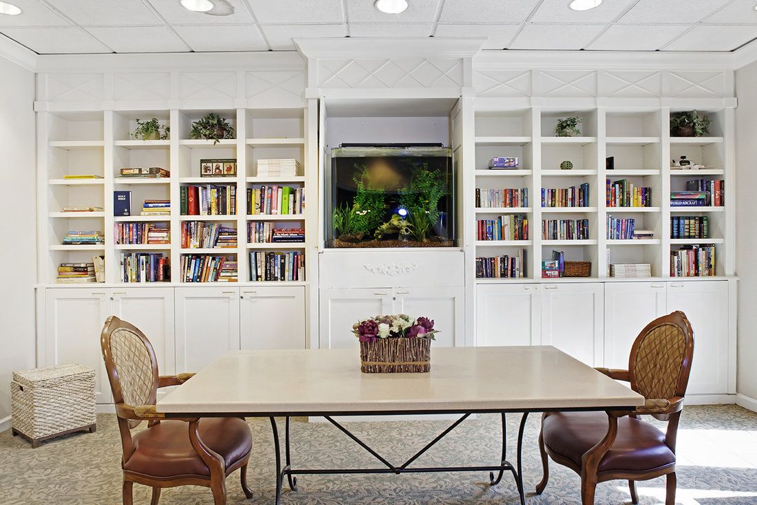 A cozy reading area with built-in bookshelves and a central table, complemented by an aquarium as a focal point.