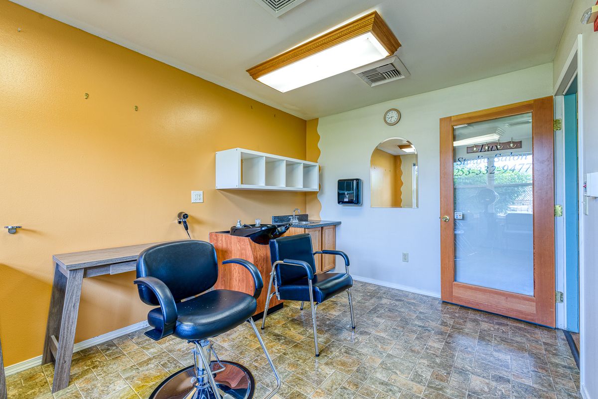 A brightly lit hair salon with chairs and a mirror.