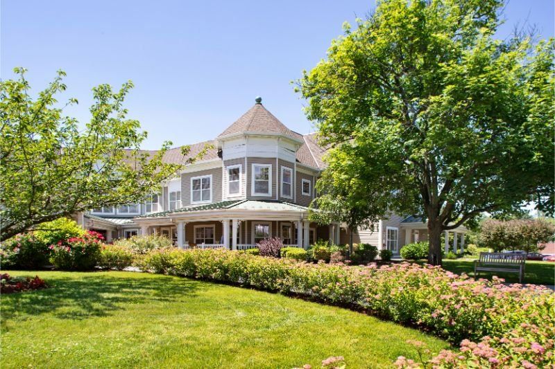A large house with a lush garden and trees surrounding it.