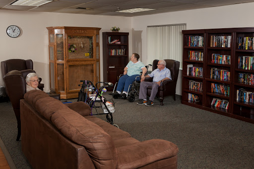 Two elderly individuals, one in a wheelchair, relax in a cozy living room setting.
