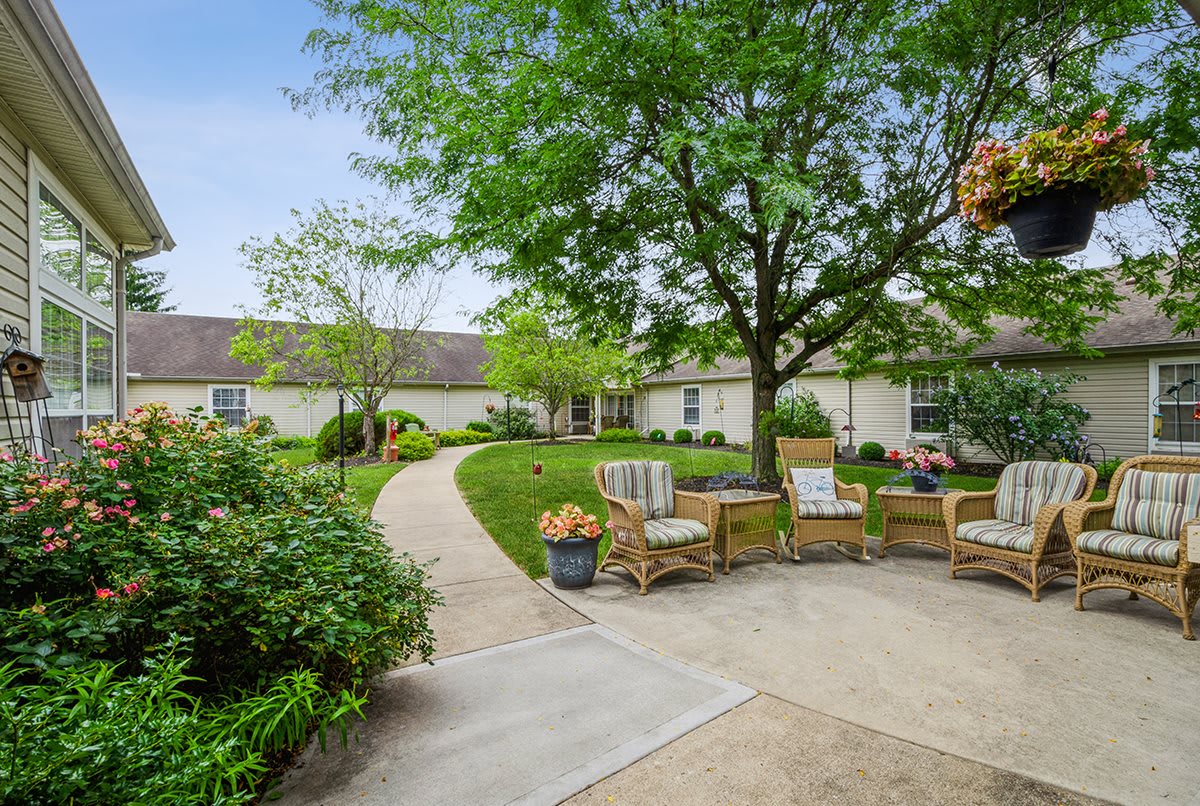 A serene outdoor patio area with comfortable seating surrounded by lush greenery and a well-maintained garden path.