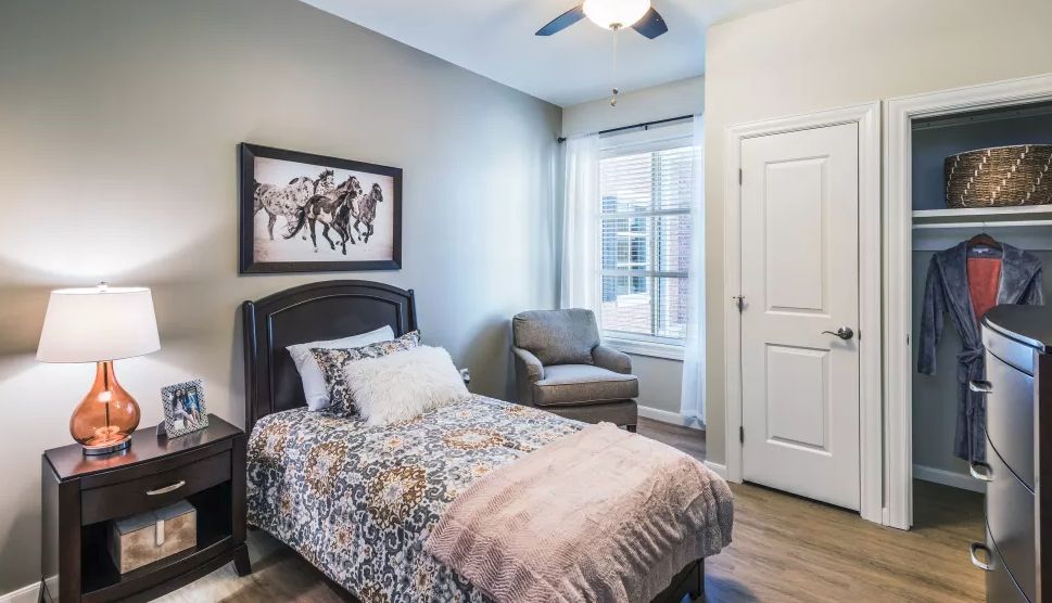 A cozy bedroom with a single bed, armchair, and large window.