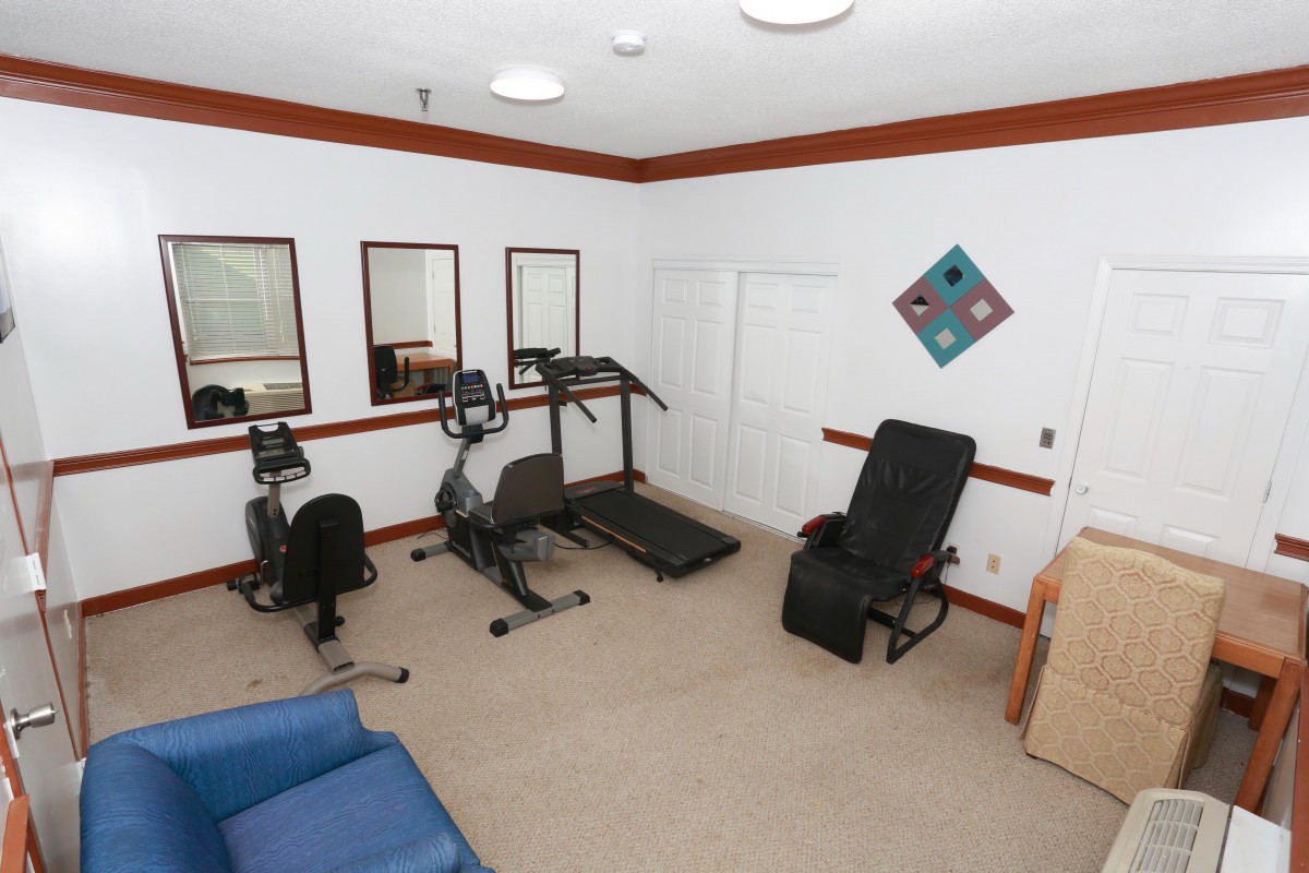 A small home gym with exercise equipment including a treadmill and stationary bike, surrounded by mirrors.