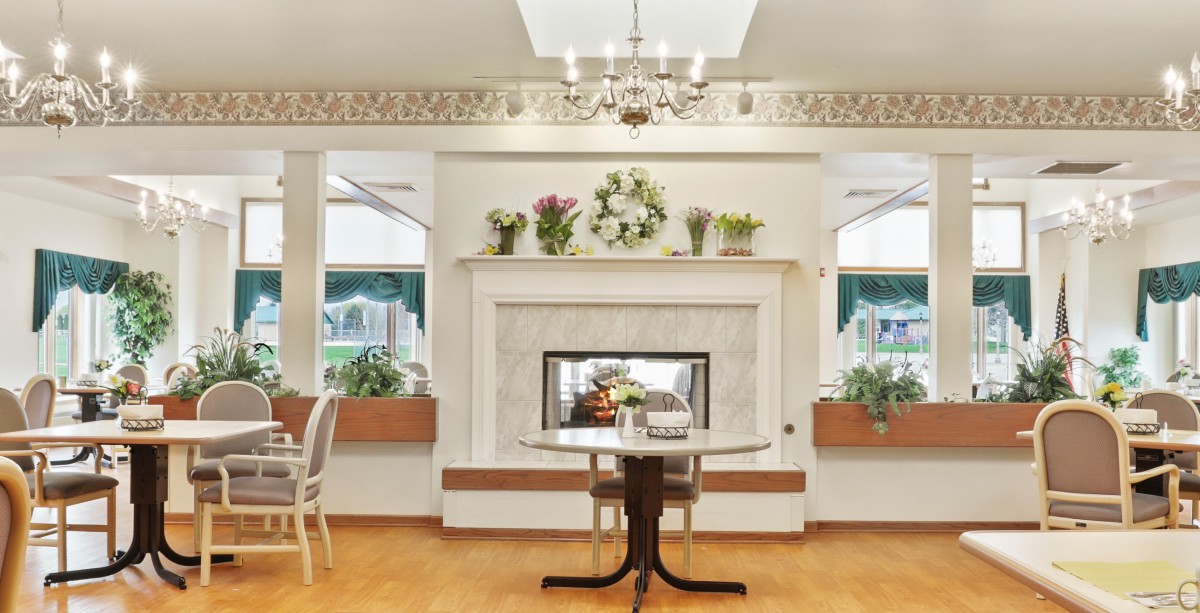 A cozy living room with an elegant fireplace, adorned with floral decorations and a classic chandelier.