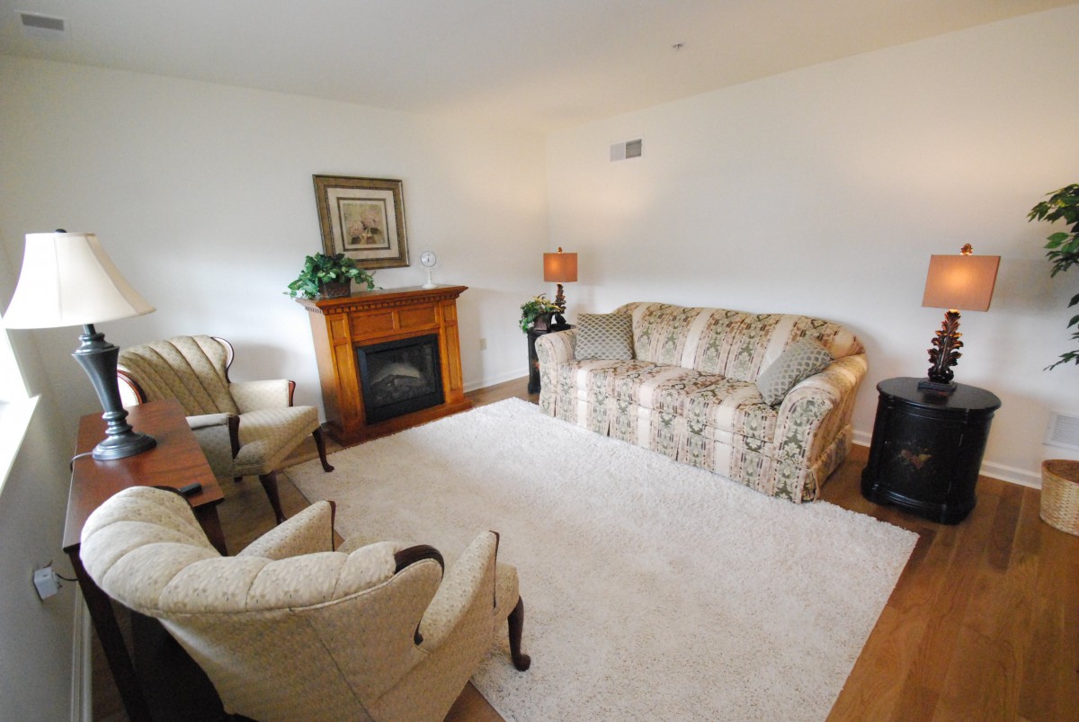 A cozy living room with a sofa, chairs, a fireplace, and a carpet.