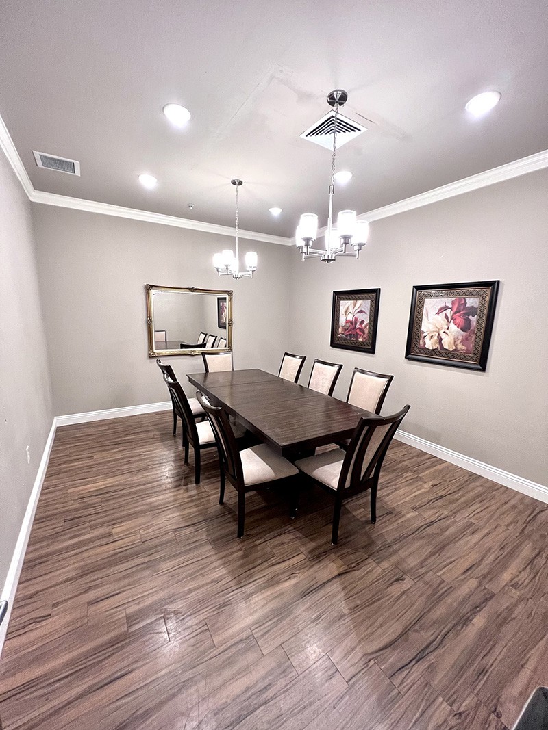 A modern dining room with a sleek table, chairs, and elegant chandelier.