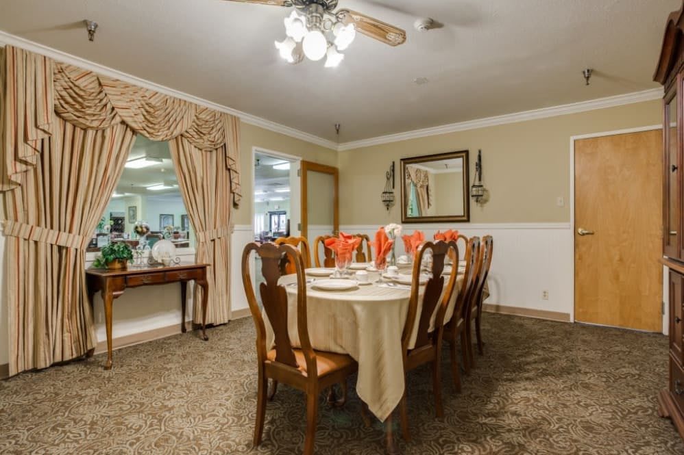 A cozy dining room with a set table, elegant chandeliers, and classic decor.