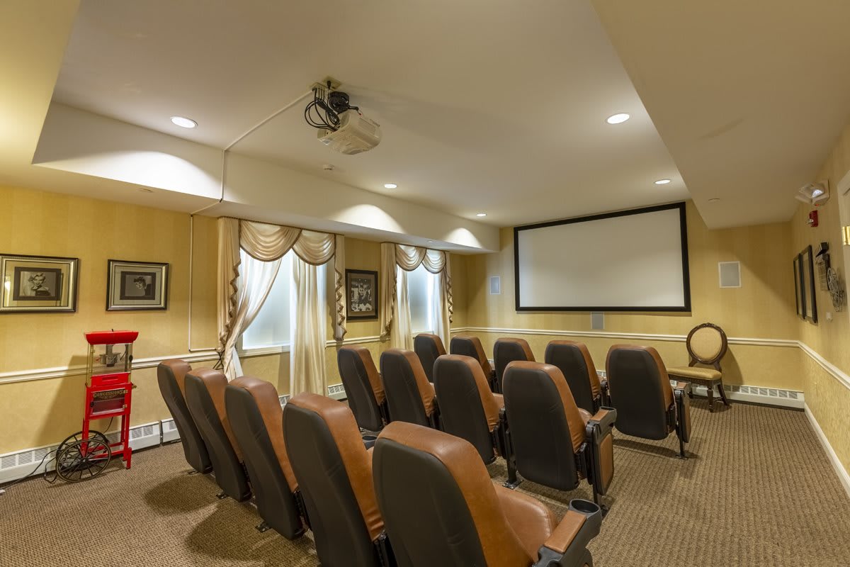 A cozy home theater with rows of seating facing a large screen and projector.
