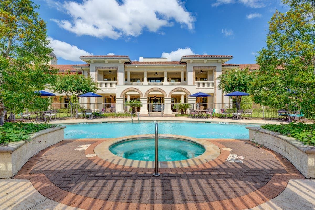 A luxurious outdoor swimming pool in front of a grand resort building under a clear blue sky.
