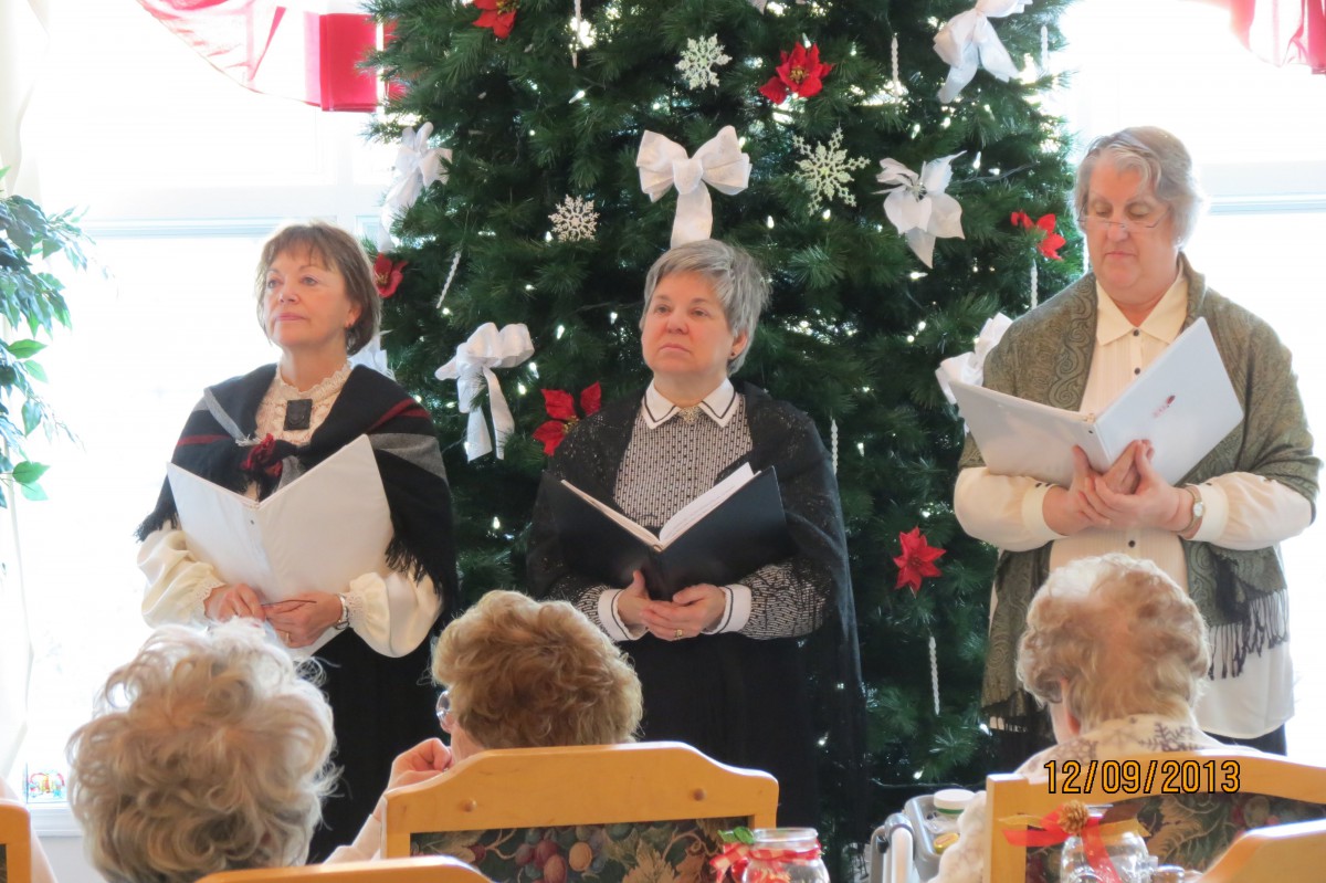 A choir performs in front of a decorated Christmas tree.