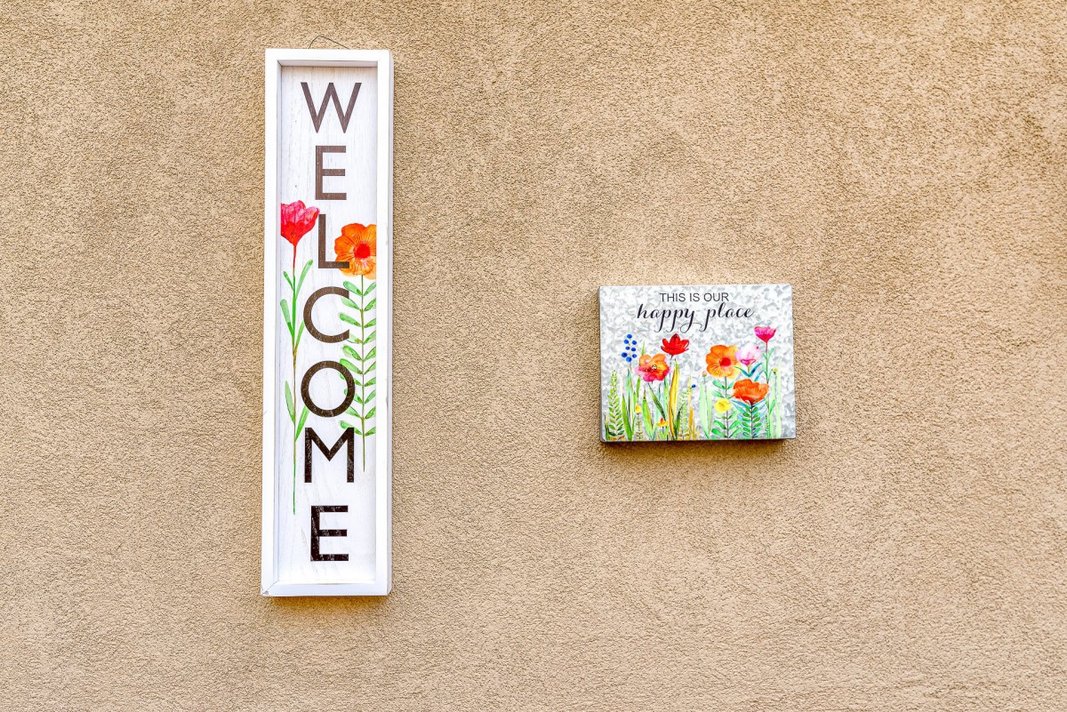 A welcoming wall display with a floral-themed sign and decor.