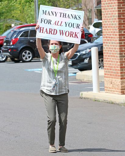 A person holding a sign expressing gratitude for the hard work of others.